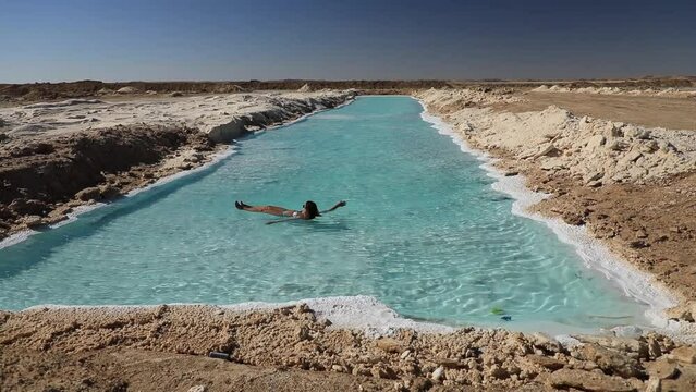 A beautiful young woman swims in Salt Plains and Lakes in Siwa Oasis, Egypt