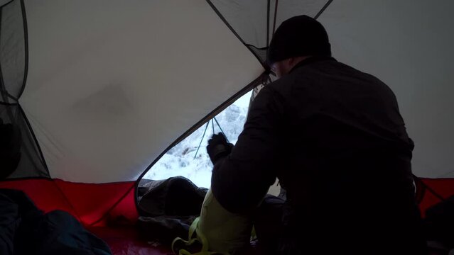 A man inside a tent setting up his camping sleeping bag and equipment