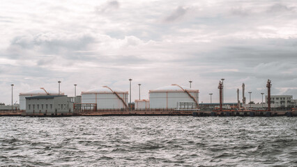 Fototapeta premium Grey sea waters stretch in the foreground, with aviation fuel storage tanks at Male's airport in the background, showcasing the vital infrastructure of the Maldives