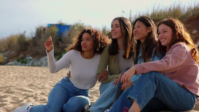 Four girls sitting on beach.