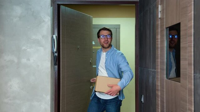 Young man moving into new apartment holding cardboard boxes with belongings
