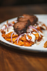 Tasty breakfast - chilaquiles with flank steak, cream cheese and onion