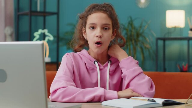 Oh my God, Wow. Caucasian preteen school girl using laptop surprised looking at camera with big eyes, shocked by sudden victory, good win news, celebrating. Excited amazed child, kid at home workplace