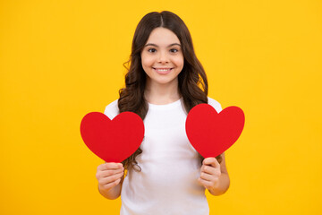 Lovely romantic teenage girl hold red heart symbol of love for valentines day isolated on yellow background. Happy teenager, positive and smiling emotions of teen girl.