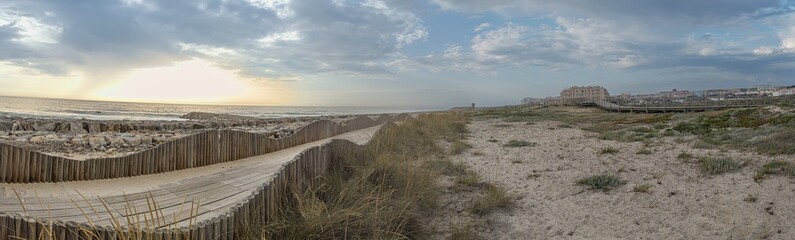 A wood pedestrian walkways, build over a sand dune that is used to give beach access in Furadouro beach, glows at sunset. Ovar, Aveiro, Portugal, Europe