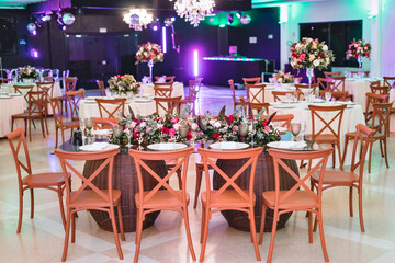 a glass dining table decorated with plates and flowers, with wooden chairs around it