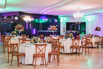 a glass dining table decorated with plates and flowers, with wooden chairs around it