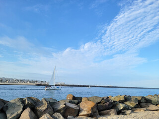 Fototapeta na wymiar Yacht sailing through Entrance Channel from Mission Bay to Pacific Ocean in San Diego, California