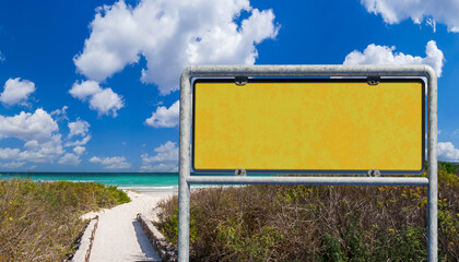 Entrance to the beach. Metal pointer on the background of the beach.  Yellow signboard on the...