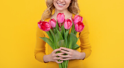 smiling young girl with spring tulip flowers on yellow background