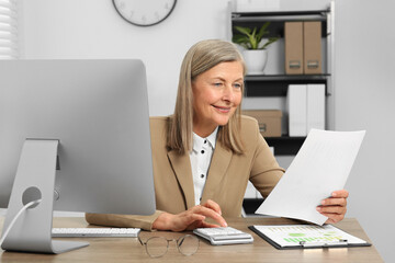 Senior accountant working at wooden desk in office