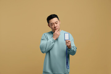 Emotional asian man with vip pass badge on beige background