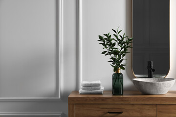 Eucalyptus branches and folded towels near stylish vessel sink on bathroom vanity, space for text. Interior design