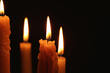 Burning candles on black background, closeup. Space for text