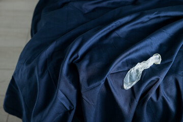 Unrolled condom on bed, above view. Safe sex