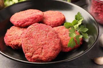 Delicious beetroot cutlets and parsley in black bowl, closeup. Vegan dish