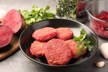 Delicious beetroot cutlets and parsley in black bowl on light gray table. Vegan dish