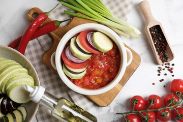 Dressing for delicious ratatouille and different vegetables on white marble table, flat lay