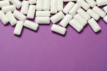 Tasty white chewing gums on purple background, flat lay. Space for text