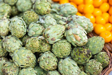 Obraz premium Pile of fresh artichoke globes on counter in grocery store. Organic vegetables. Healthy natural vegetarian product concept