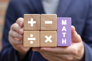 Student holding colorful blocks with mathematical operations symbols of plus, minus, multiply and divide and sees text: MATH. Concept of education, business, math or calculation. Mathematics, algebra.