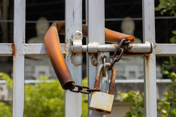 A locked gate in front of a building with seated Buddha statues, Thailand