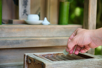 Hand making a offering in wooden offering box or Saisen Box, in Japanese Temple, Kyoto, Japan.