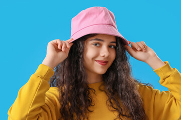 Teenage girl in pink bucket hat on blue background, closeup