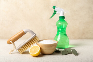 Bowl of baking soda, sprayer, cleaning brush and lemon on light table