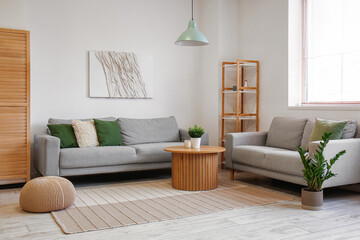 Interior of light living room with grey sofas and houseplant on coffee table