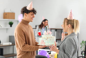 Young man greeting his colleague with Birthday cake at party in office