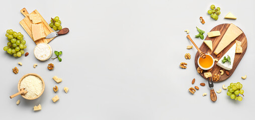 Different types of tasty cheese, honey and grapes on grey background