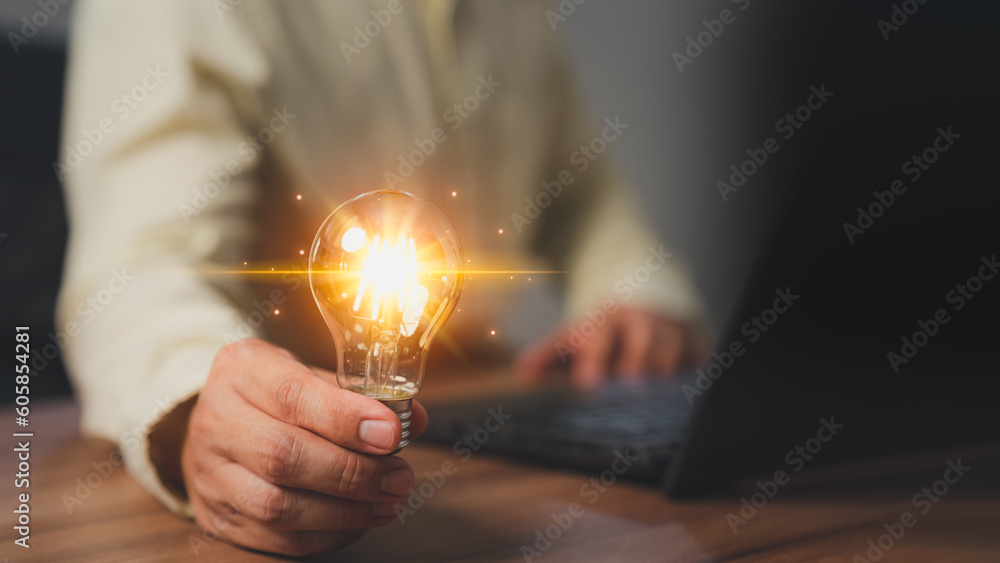 Aufkleber man holding a light bulb while working on a computer laptop to think and generate new ideas through 