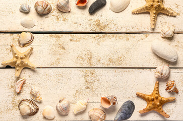 Frame made of seashells and starfishes with sand on white wooden background
