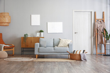 Interior of light living room with grey sofa and drawers