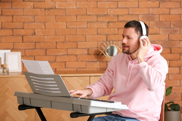 Male musician playing synthesizer at home