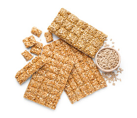 Bowl with sunflower seeds and tasty kozinaki on white background
