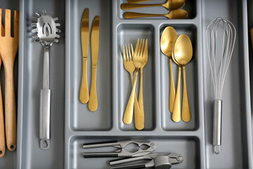 Open kitchen drawer with different gold cutlery