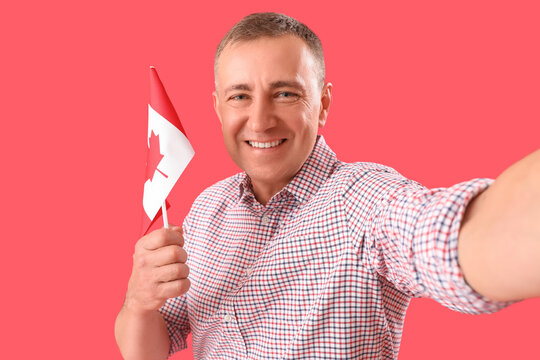 Mature man with flag of Canada taking selfie on red background, closeup - Powered by Adobe