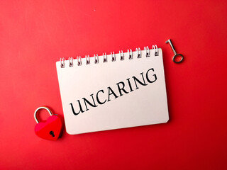 Notebook and love padlock with the word UNCARING