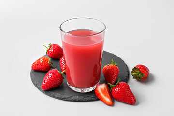 Board with glass of tasty strawberry juice on grey background