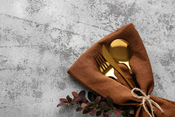 Fototapeta na wymiar Golden cutlery and barberry twig in napkin on grey grunge background