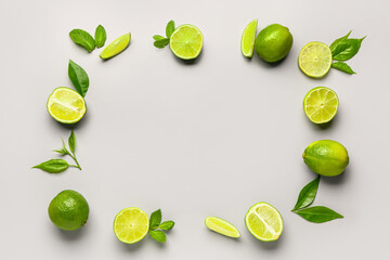 Frame made of fresh limes with mint and leaves on grey background