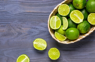 Wicker bowl with fresh limes on blue wooden background