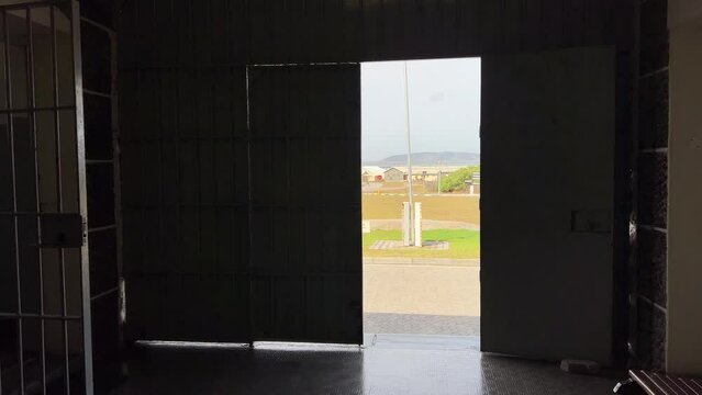 Open entrance prison door on Robben Island with trees in the wind
