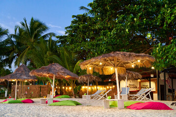 Beach umbrella made of dried palm fronds on a tropical island beach. A luxurious vacation concept