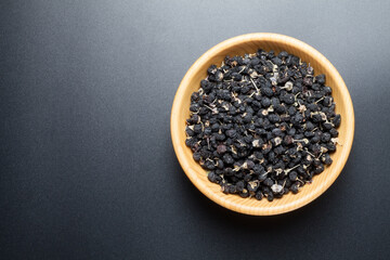 black Chinese wolfberry in a wooden bowl. top view.