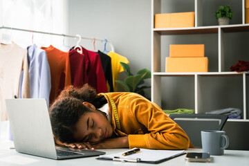 African american designer woman sleeping on desk in atelier after exhausted from designing clothes