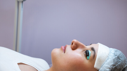 Close-up portrait of a woman on the procedure of lamination and tinting of eyelashes. Permanent...