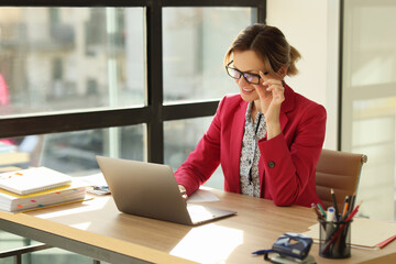Obraz premium Positive woman takes off glasses with hand looking at screen